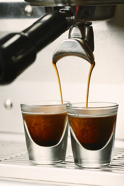 Close up action photo of a double shot espresso extraction into shot glasses.