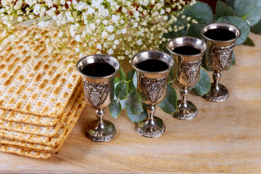Wine with kosher four glasses a of matzah a Passover Haggadah on a wood background