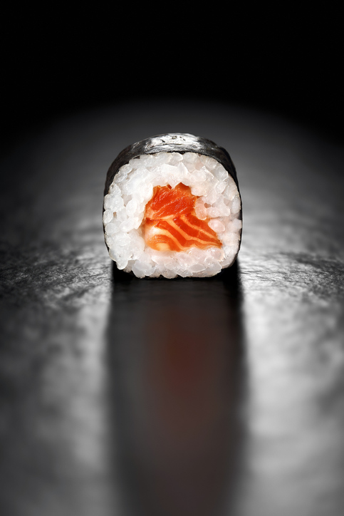 Maki Sushi Roll with Salmon and Rice wrapped in Nori on a black background