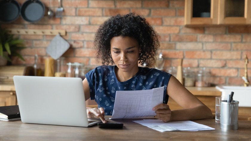 Millennial biracial woman manage household finances in kitchen