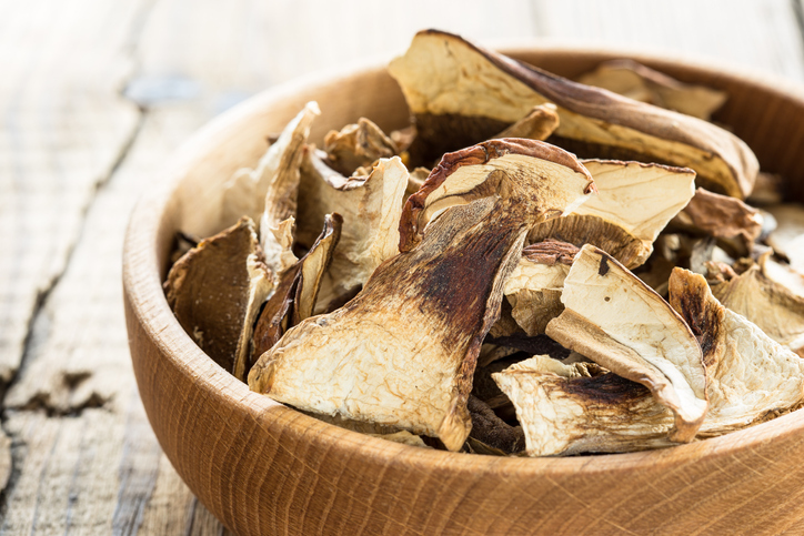 Dried porcini mushrooms in wooden bowl on a rustic wooden table